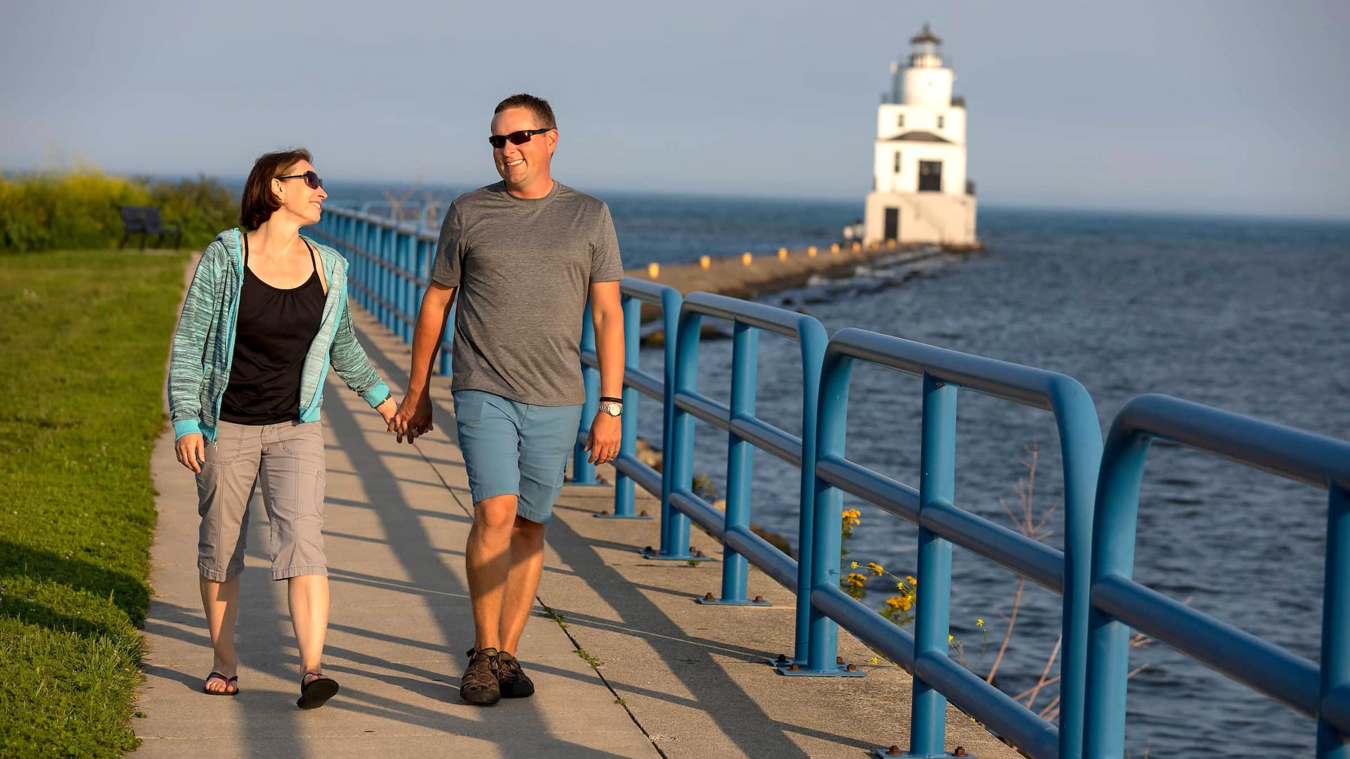Couple walking along Lake Michigan with Manitowoc Lighthouse in background